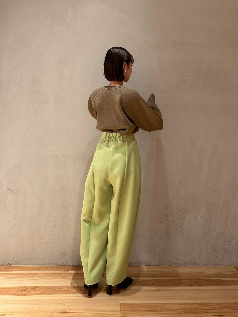 グリーン系のその他パンツ、ベージュ系のニット/セーター、ブラック系のブーティを着用したレディースの冬コーディネートの3枚目の写真