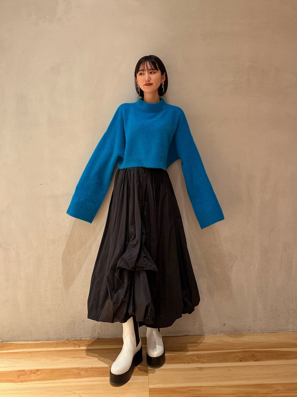 ブラック系のスカート、ブルー系のニット/セーター、ホワイト系のブーツを着用したレディースの冬コーディネートの3枚目の写真