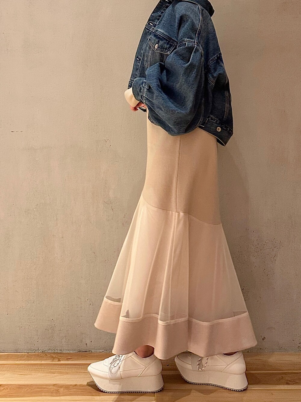 ブルー系のデニムジャケット、ベージュ系のワンピース、ホワイト系のスニーカーを着用したレディースの春コーディネートの3枚目の写真