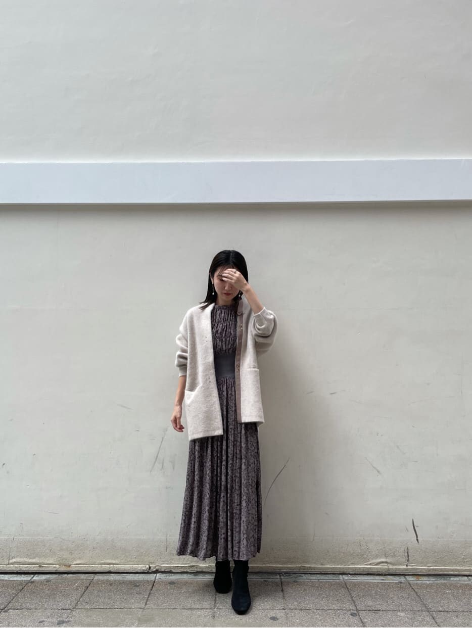 グレー系のワンピース、ホワイト系のカーディガン/ボレロ、ホワイト系のピアス（両耳用）を着用したレディースの秋コーディネートの2枚目の写真