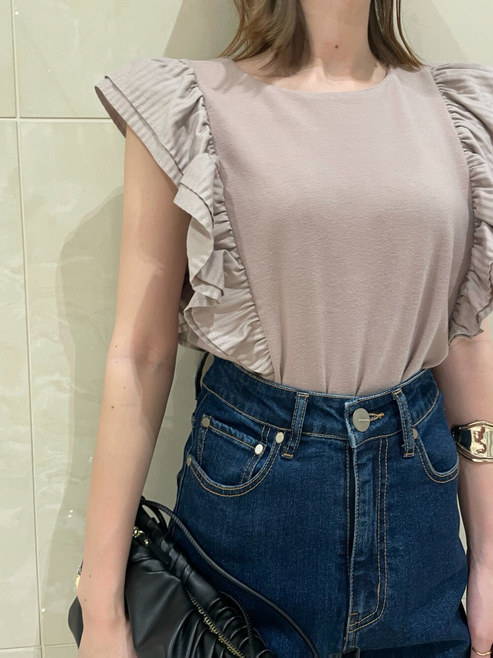 ブルー系のデニムパンツ、ブラック系のハンドバッグ、ブラック系のサンダルを着用したレディースの春コーディネートの2枚目の写真