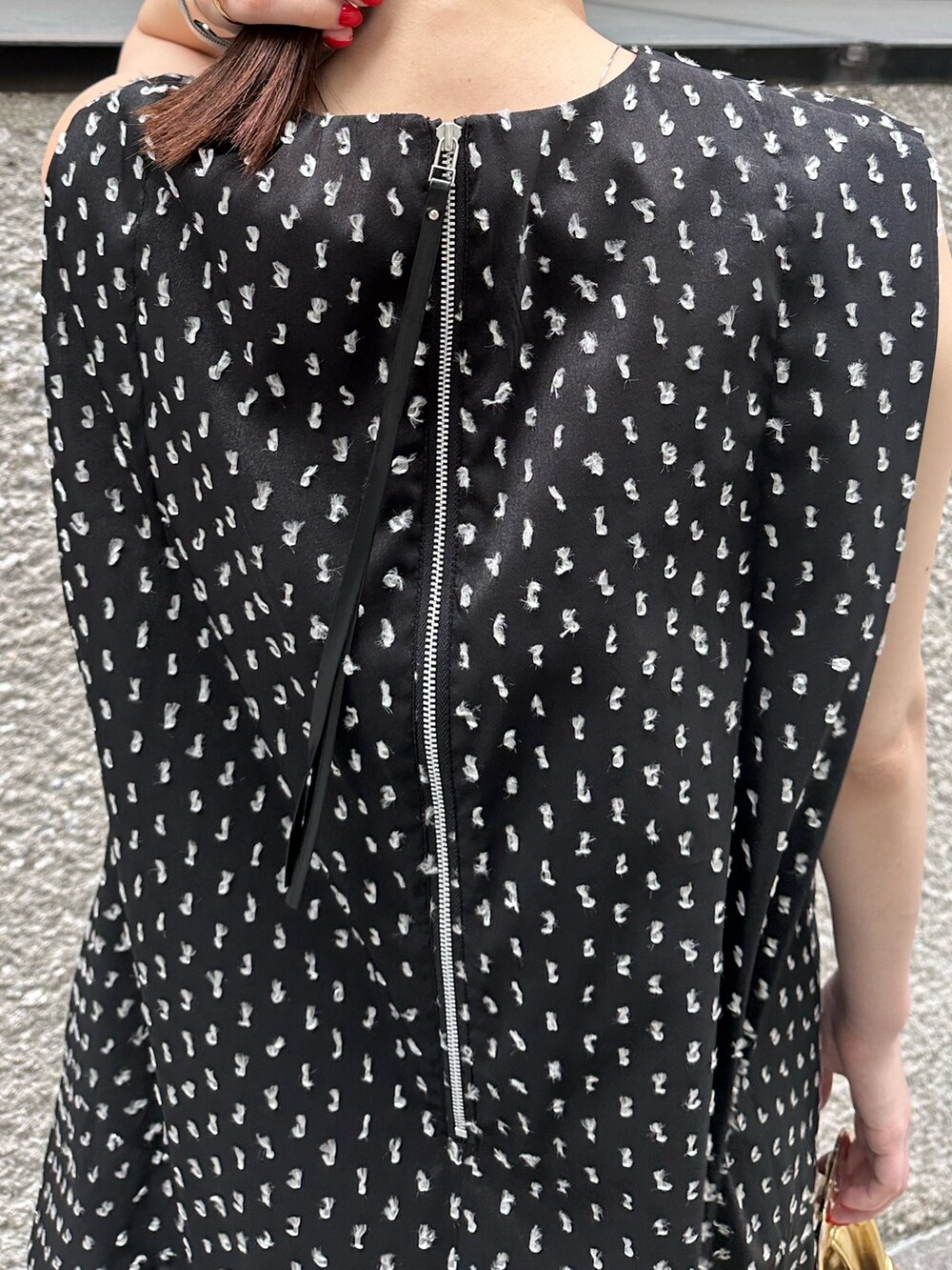 ブラック系のワンピース、ゴールド系のハンドバッグ、ゴールド系のパンプスを着用したレディースの夏コーディネートの8枚目の写真