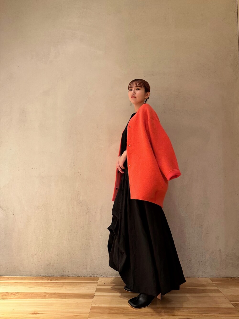 ブラック系のニット/セーター、ブラック系のブーツ、ピンク系のノーカラージャケットを着用したレディースの夏コーディネートの4枚目の写真