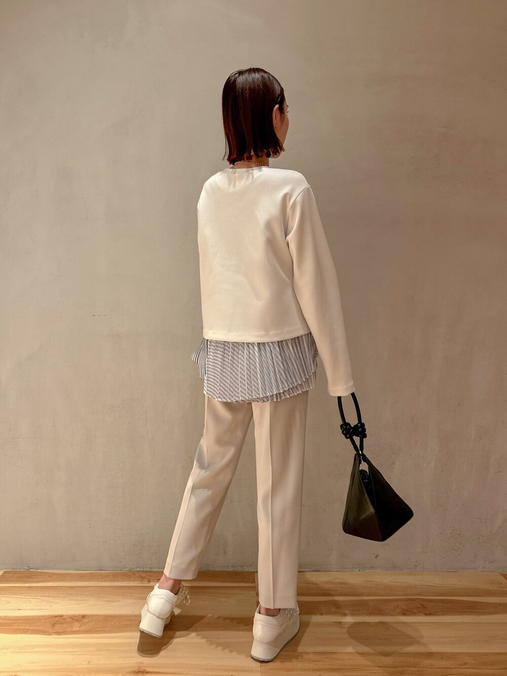 ホワイト系のスニーカー、ブラック系のハンドバッグ、グレー系のその他パンツを着用したレディースの冬コーディネートの2枚目の写真