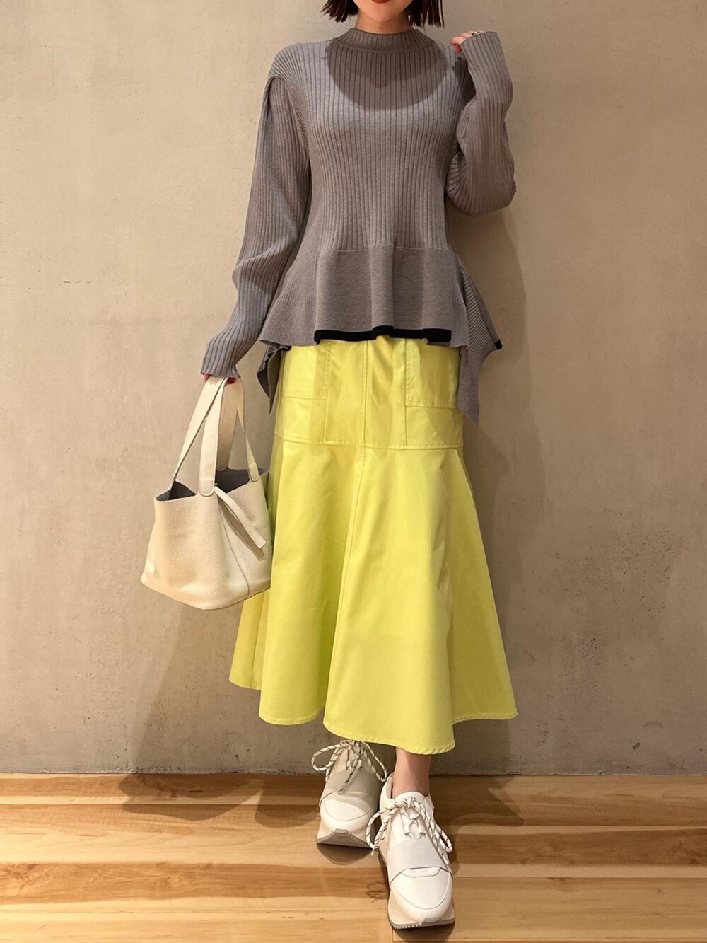 グレー系のニット/セーター、イエロー系のスカート、ホワイト系のスニーカーを着用したレディースの冬コーディネートの3枚目の写真