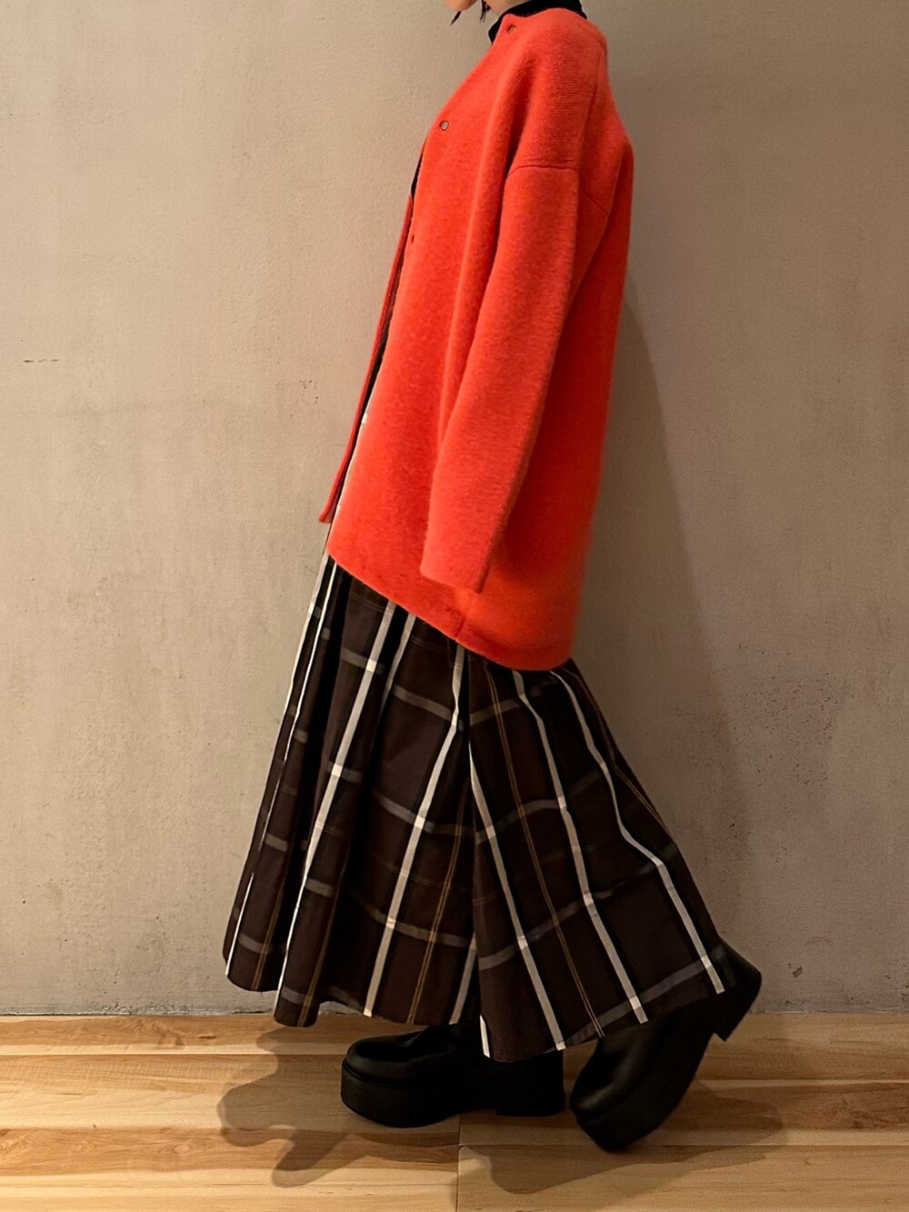 ピンク系のノーカラージャケット、ブラウン系のスカート、ブラック系のブーツを着用したレディースの夏コーディネートの4枚目の写真