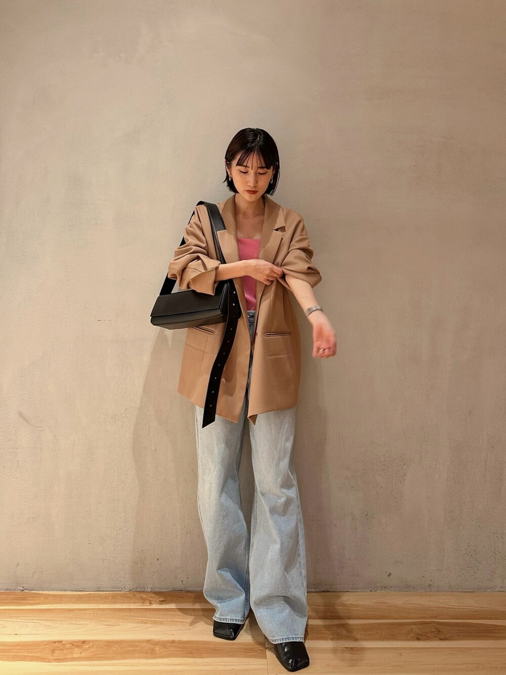 ブルー系のデニムパンツ、ブラック系のパンプス、ブラック系のショルダーバッグを着用したレディースの冬コーディネートの2枚目の写真