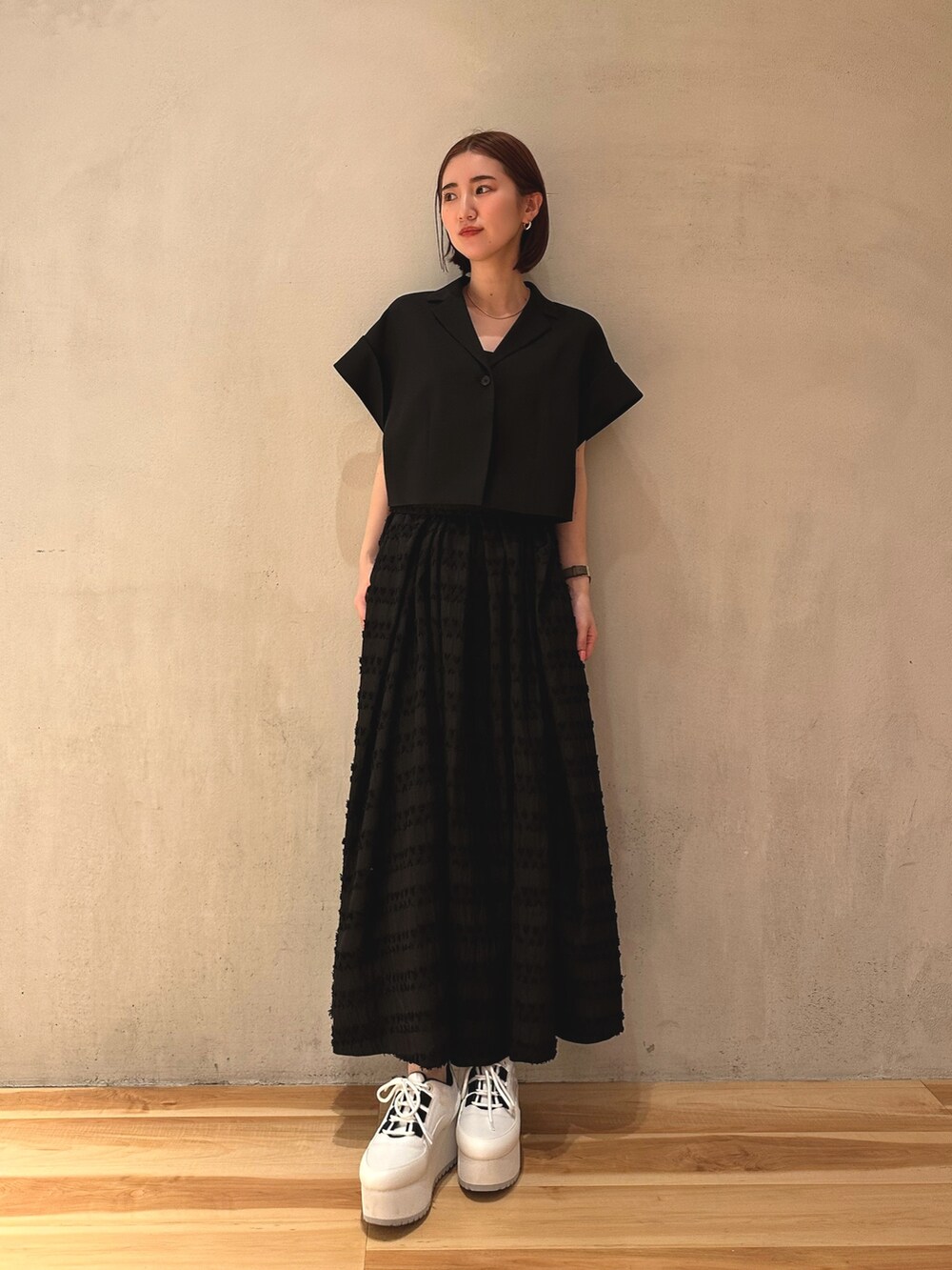 ブラック系のテーラードジャケット、ホワイト系のスニーカー、ブラック系のスカートを着用したレディースの春コーディネートの2枚目の写真