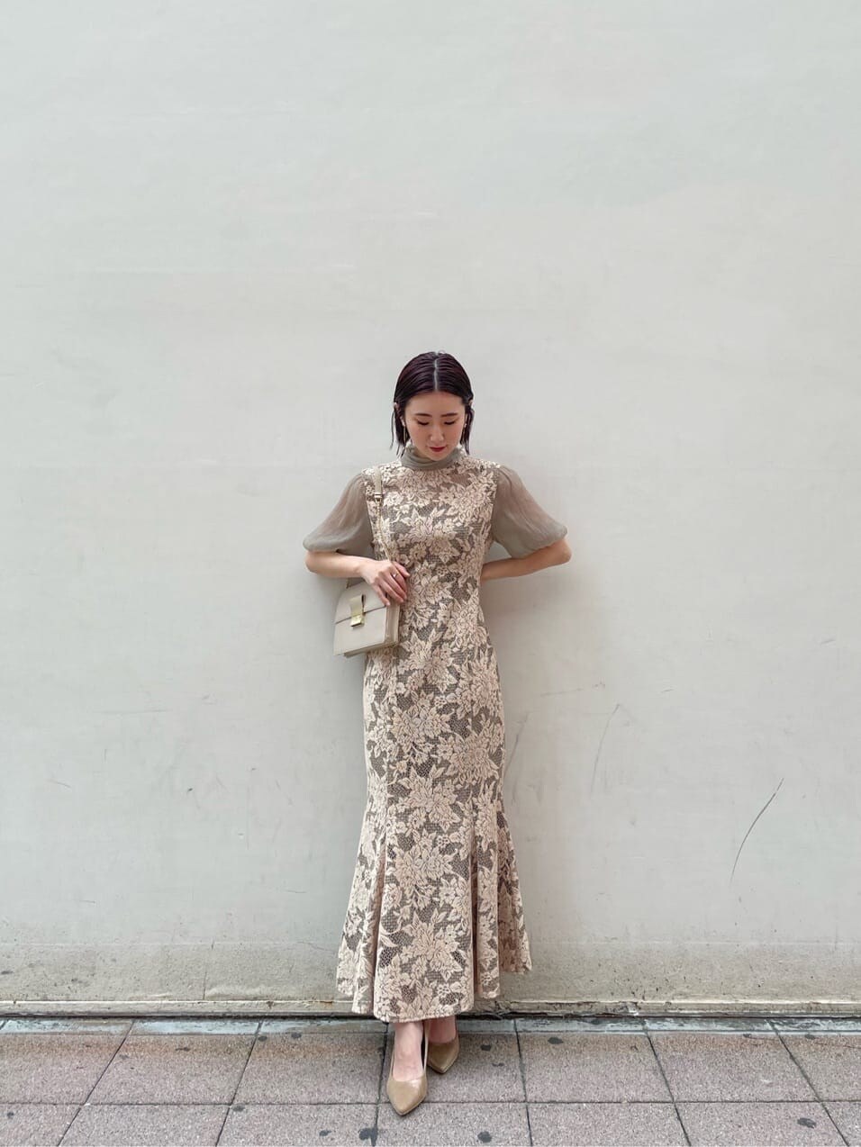 ベージュ系のドレス、ゴールド系のパンプス、ベージュ系のクラッチバッグを着用したレディースの夏コーディネートの2枚目の写真