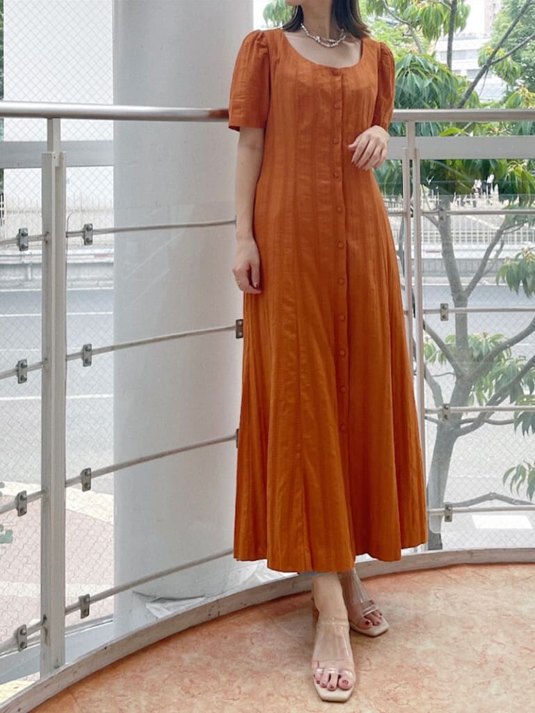 オレンジ系のワンピース、シルバー系のネックレスを着用したレディースの夏コーディネートの4枚目の写真