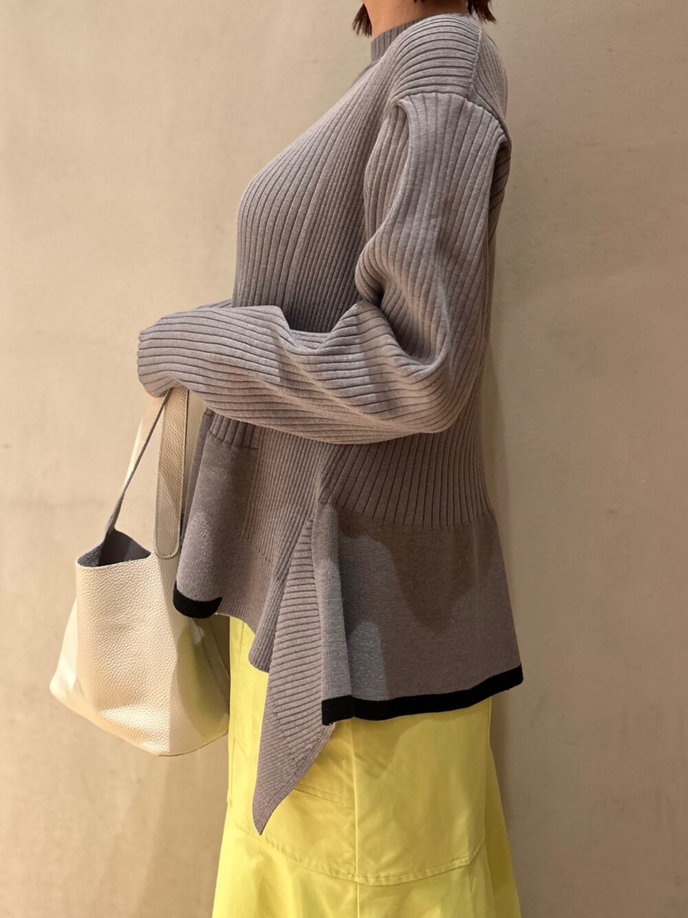 グレー系のニット/セーター、イエロー系のスカート、ホワイト系のスニーカーを着用したレディースの冬コーディネートの7枚目の写真