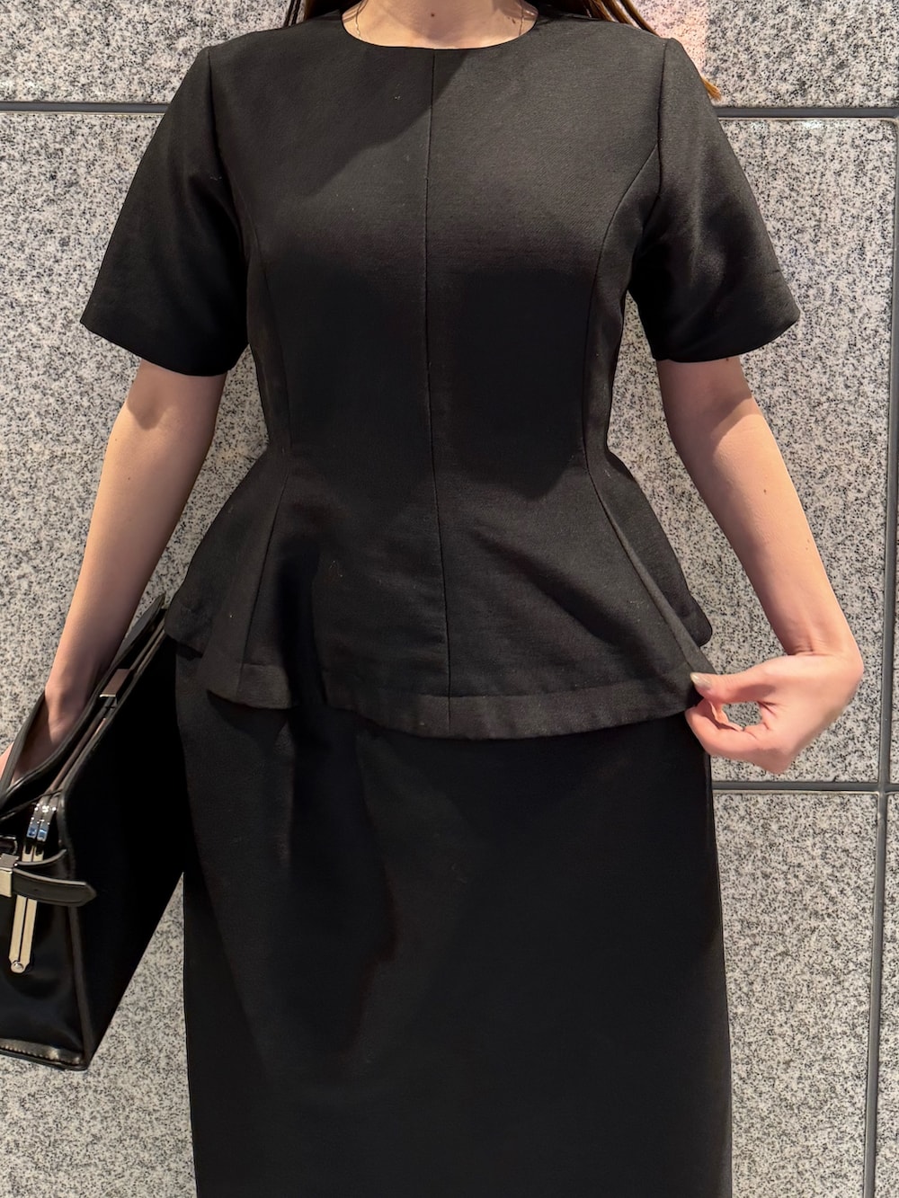 ブラック系のワンピース、ブラック系のハンドバッグを着用したレディースの冬コーディネートの8枚目の写真