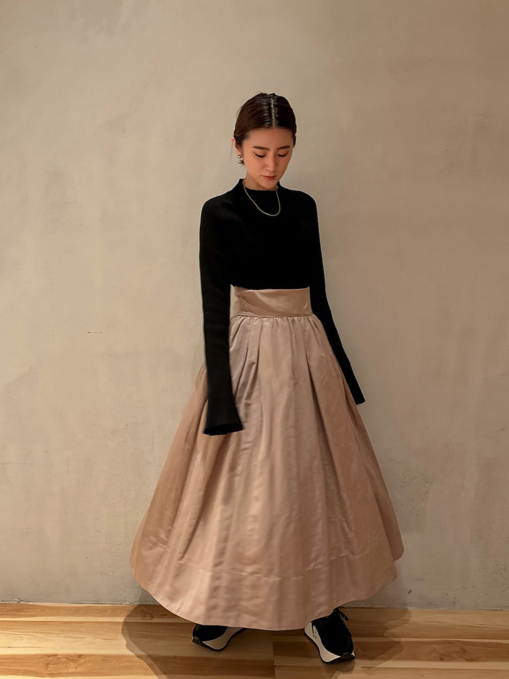 ブラック系のニット/セーター、ベージュ系のスカート、ブラック系のスニーカーを着用したレディースの冬コーディネートの2枚目の写真