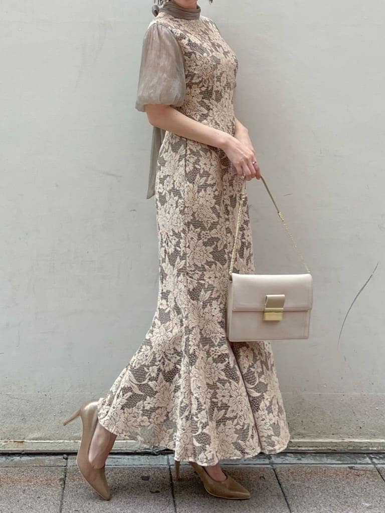 ベージュ系のドレス、ゴールド系のパンプス、ベージュ系のクラッチバッグを着用したレディースの夏コーディネートの3枚目の写真