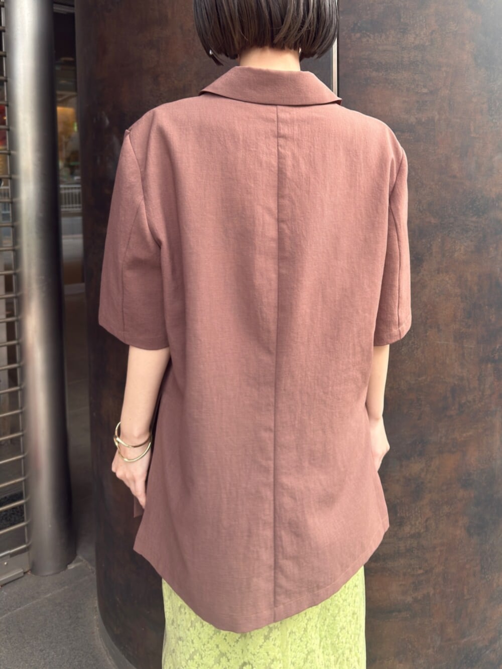 シルバー系のパンプス、ブラウン系のテーラードジャケット、グリーン系のスカートを着用したレディースの春コーディネートの7枚目の写真