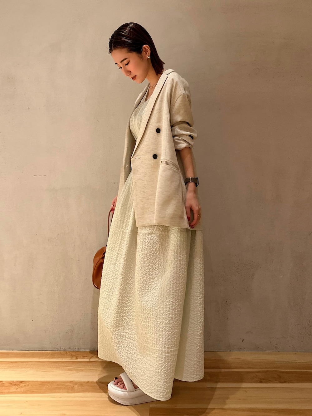 ベージュ系のテーラードジャケット、グリーン系のワンピース、ホワイト系のサンダルを着用したレディースの冬コーディネートの8枚目の写真