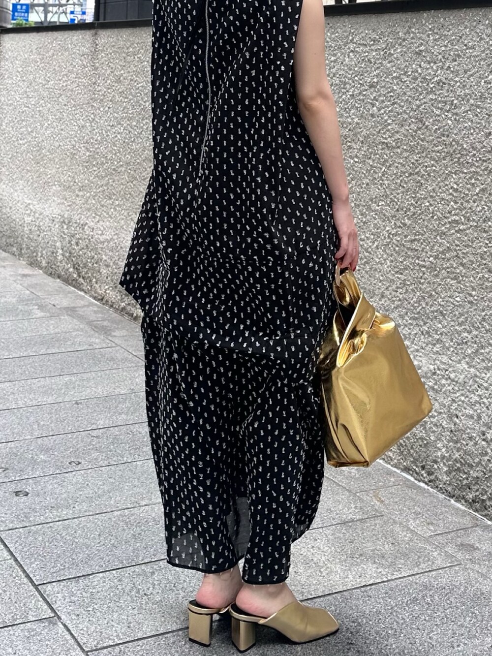 ブラック系のワンピース、ゴールド系のハンドバッグ、ゴールド系のパンプスを着用したレディースの夏コーディネートの5枚目の写真