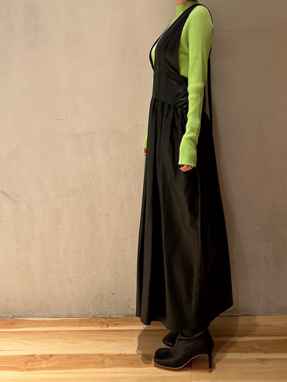 ブラック系のジャンパースカート、ブラック系のブーツ、グリーン系のニット/セーターを着用したレディースの秋コーディネートの5枚目の写真