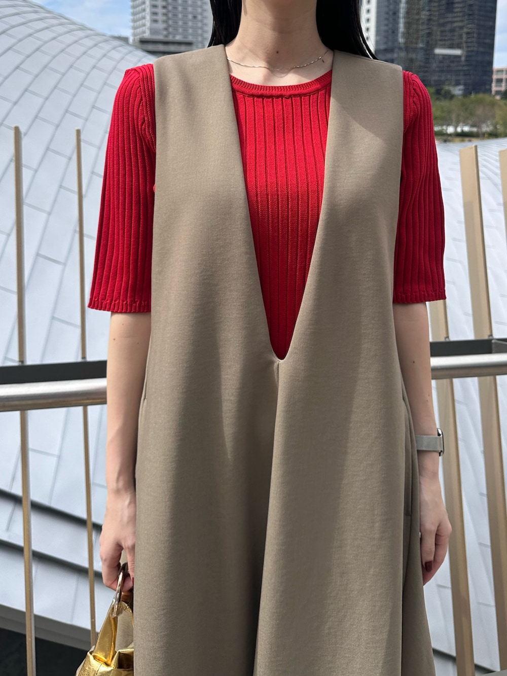 レッド系のニット/セーター、ゴールド系のハンドバッグ、ブラック系のブーツを着用したレディースの秋コーディネートの5枚目の写真