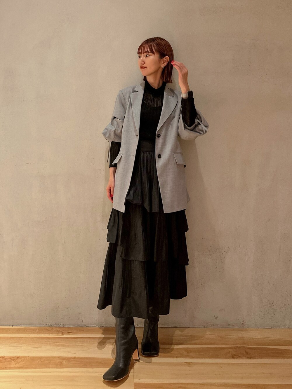 ブラック系のスカート、ブラック系のニット/セーター、グレー系のテーラードジャケットを着用したレディースの秋コーディネートの2枚目の写真