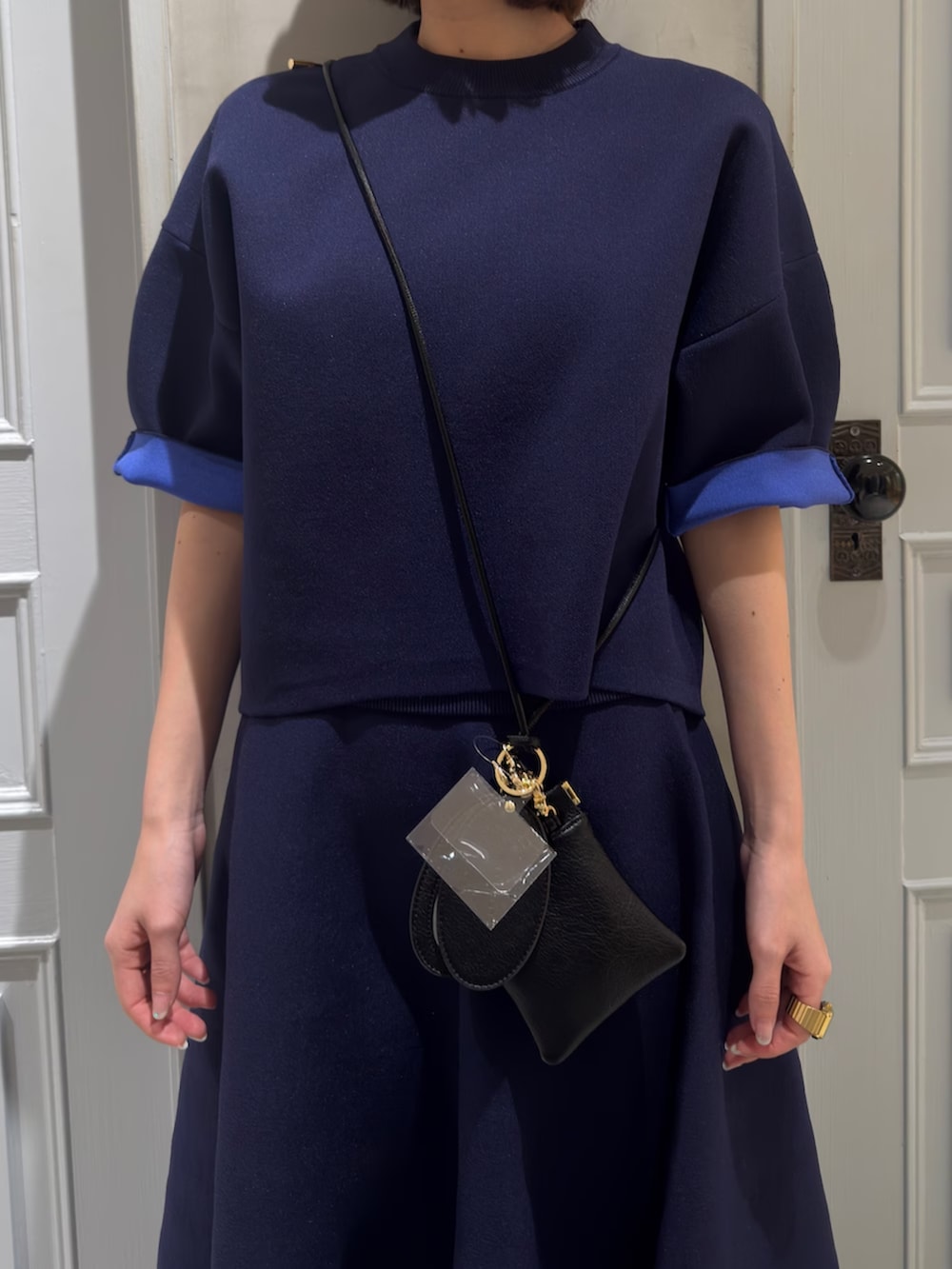 ブルー系のニット/セーター、ブルー系のスカート、ブラック系のスマホグッズを着用したレディースの春コーディネートの5枚目の写真