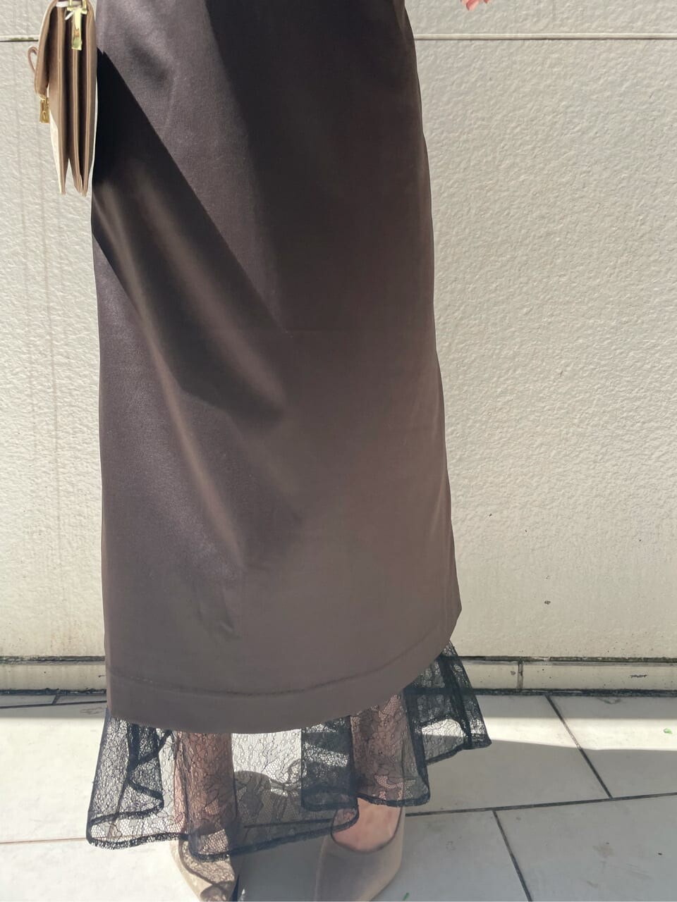 ブラック系のドレス、ベージュ系のパンプス、ベージュ系のクラッチバッグを着用したレディースの秋コーディネートの6枚目の写真