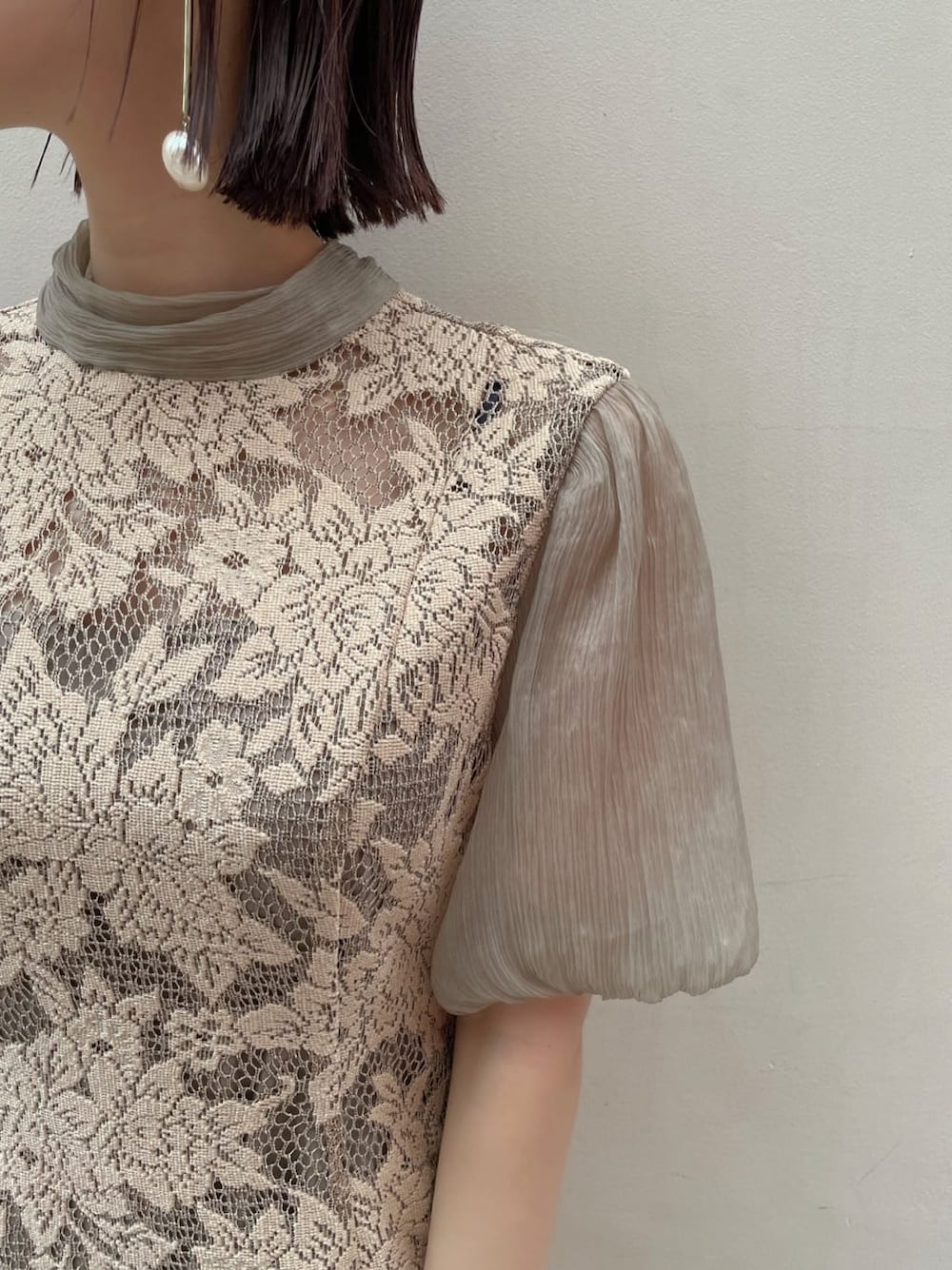 ベージュ系のドレス、ゴールド系のパンプス、ベージュ系のクラッチバッグを着用したレディースの夏コーディネートの6枚目の写真