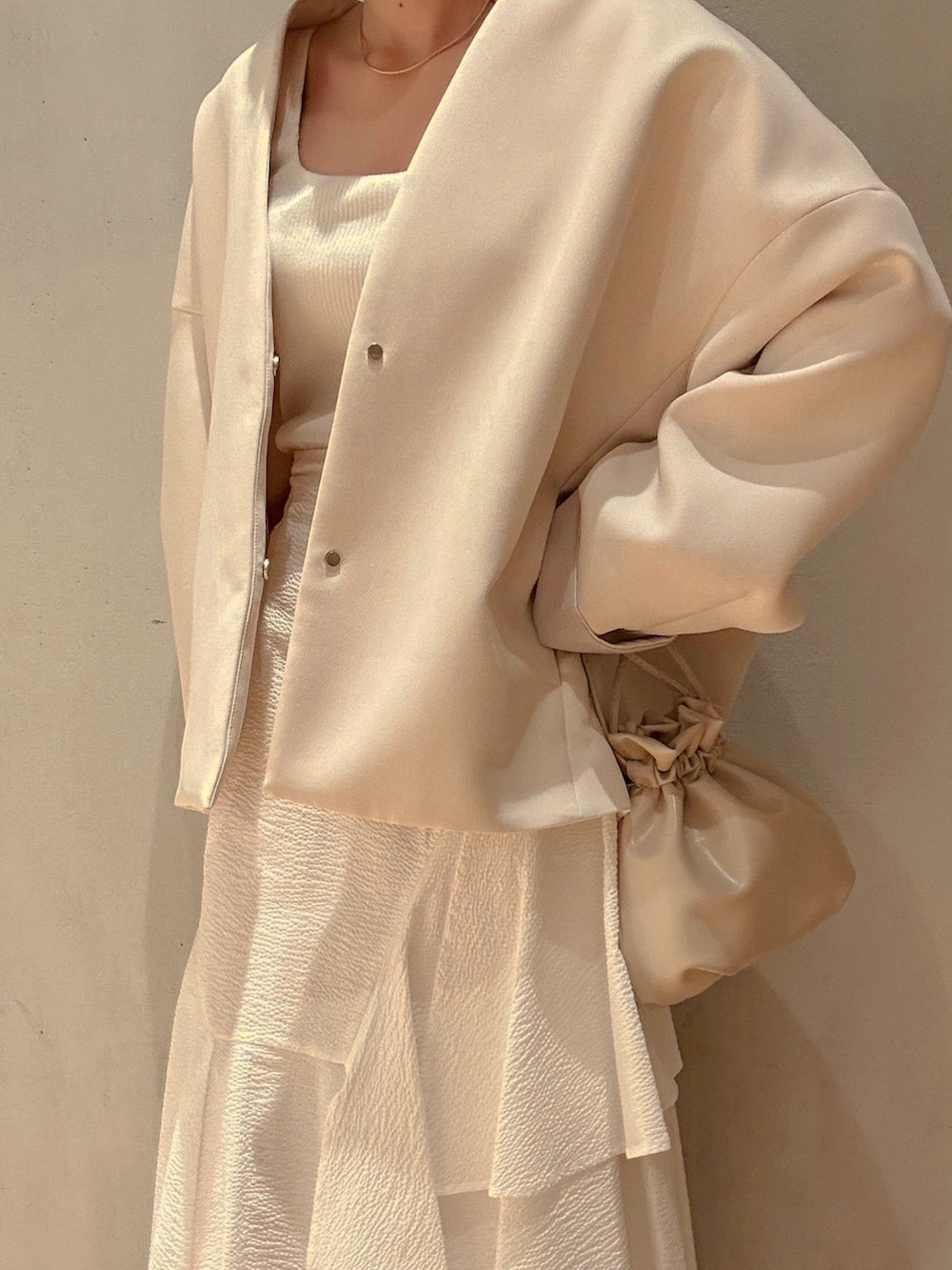 ブラウン系のノーカラーコート、ホワイト系のスカート、ホワイト系のサンダルを着用したレディースの春コーディネートの4枚目の写真