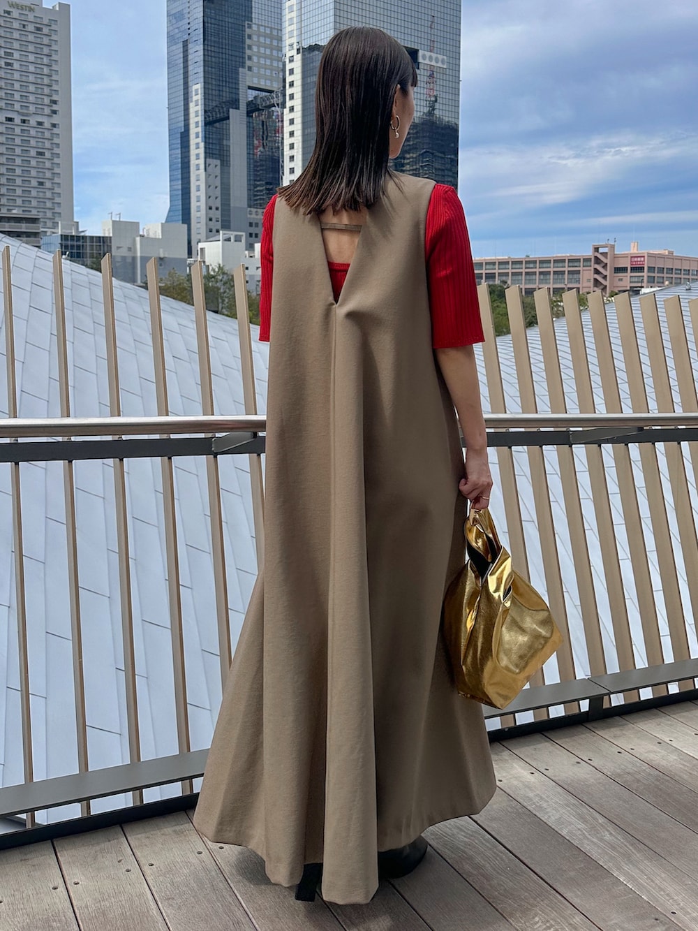 レッド系のニット/セーター、ゴールド系のハンドバッグ、ブラック系のブーツを着用したレディースの秋コーディネートの4枚目の写真