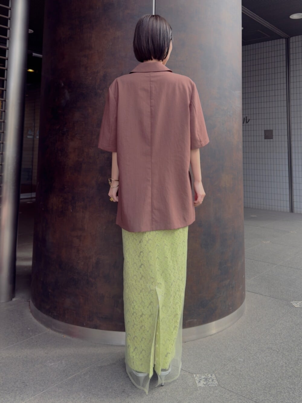 シルバー系のパンプス、ブラウン系のテーラードジャケット、グリーン系のスカートを着用したレディースの春コーディネートの3枚目の写真