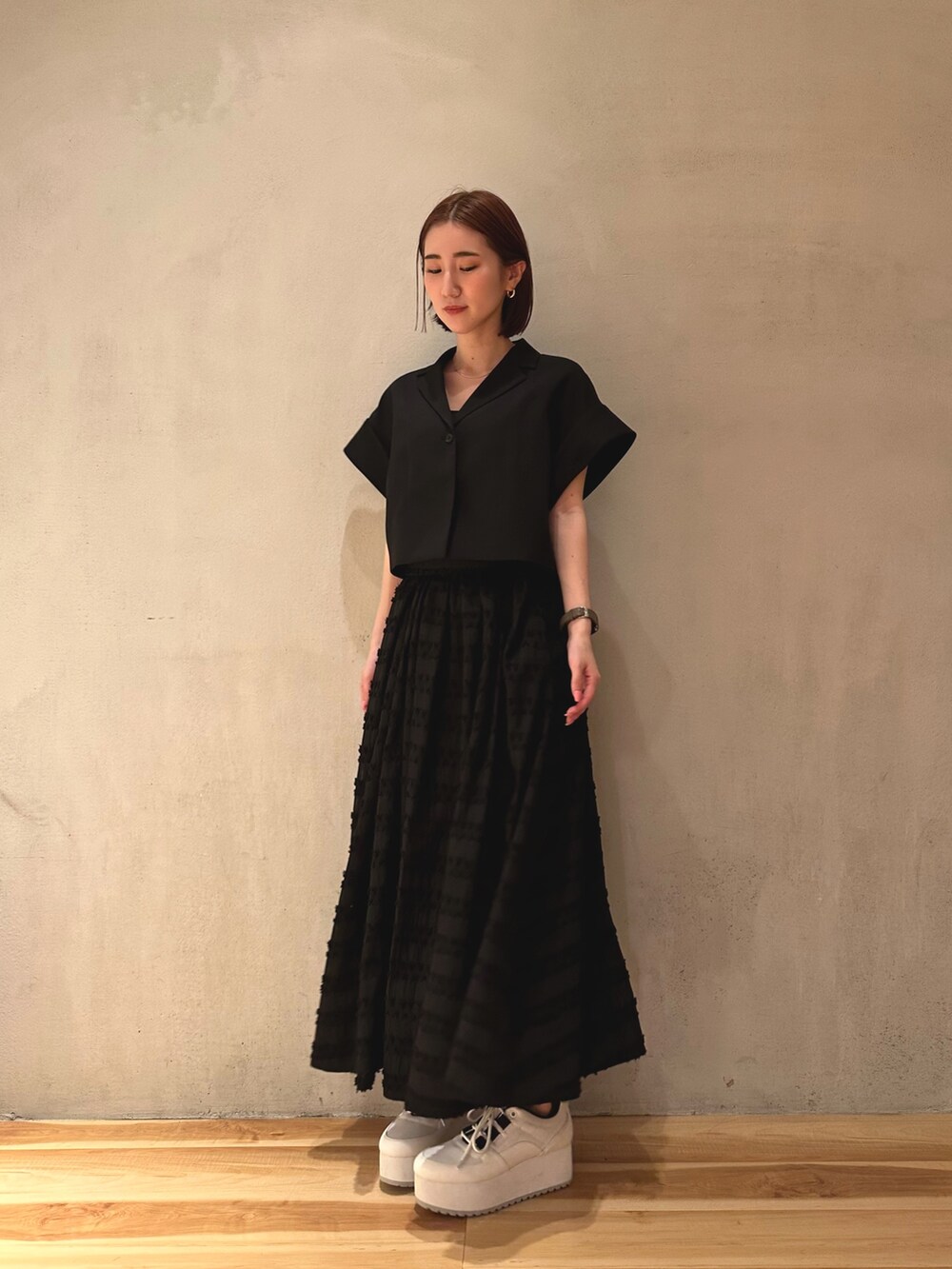 ブラック系のテーラードジャケット、ホワイト系のスニーカー、ブラック系のスカートを着用したレディースの春コーディネートの3枚目の写真