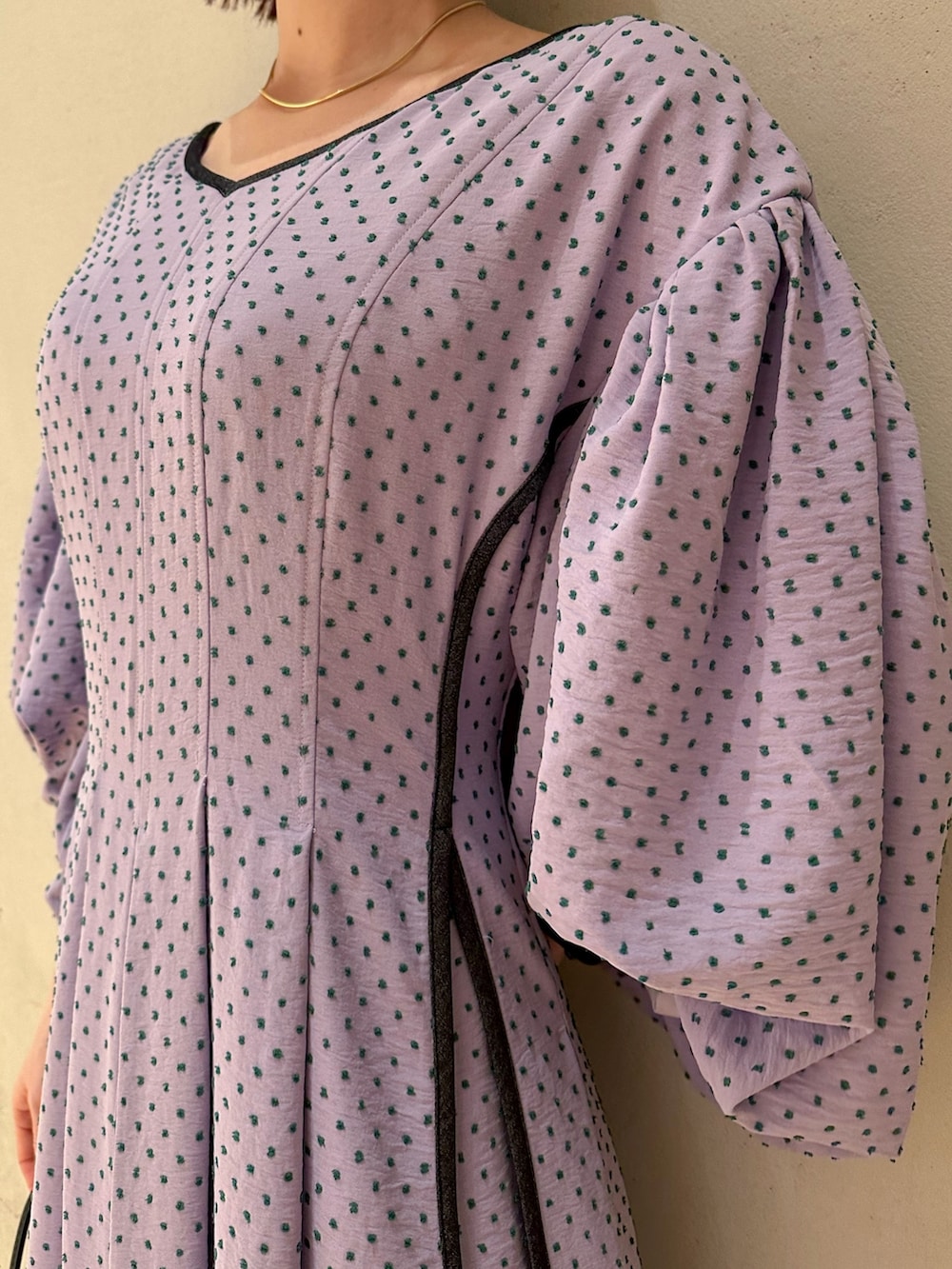 パープル系のワンピース、ベージュ系のテーラードジャケット、ブラック系のサンダルを着用したレディースの冬コーディネートの3枚目の写真