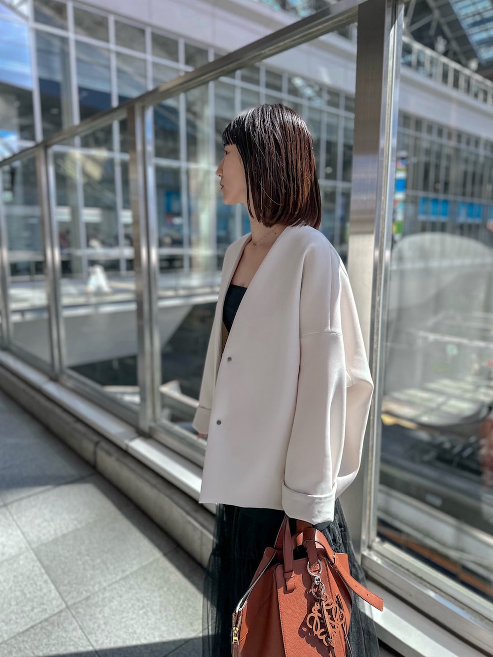 シルバー系のパンプス、ブラック系のスカート、ベージュ系のノーカラーコートを着用したレディースの春コーディネートの5枚目の写真