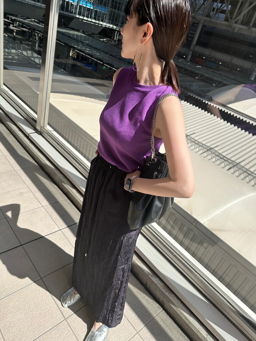 パープル系のニット/セーター、ブルー系のスカート、シルバー系のパンプスを着用したレディースの春コーディネートの2枚目の写真