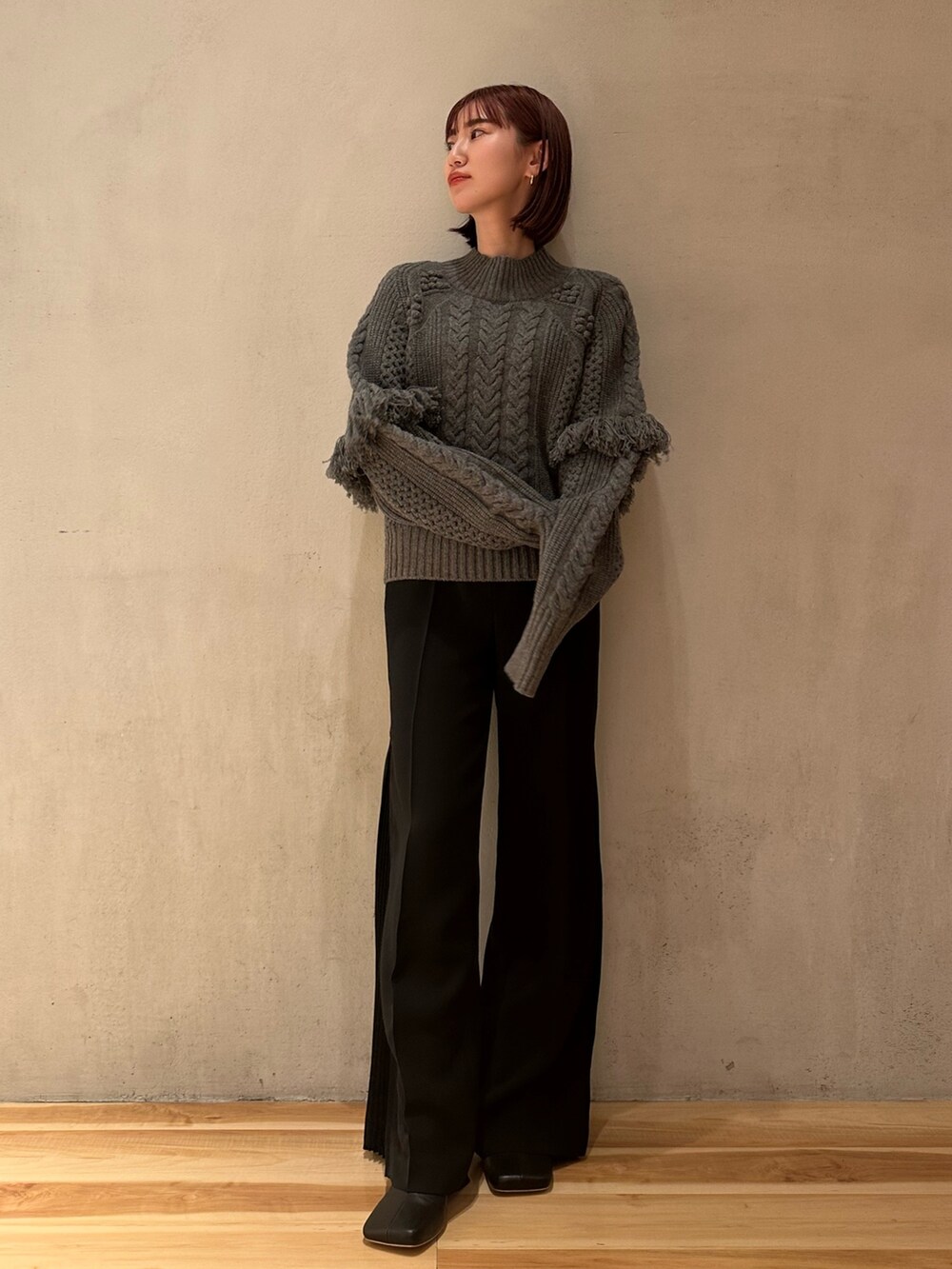 ブラック系のその他パンツ、ブラック系のブーツ、グレー系のニット/セーターを着用したレディースの春コーディネートの2枚目の写真