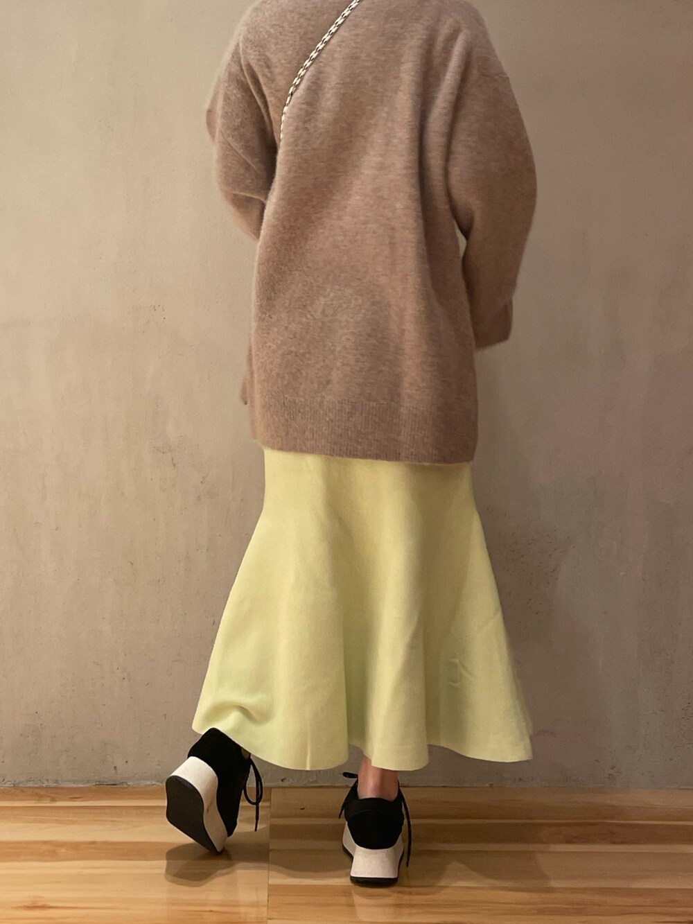 ベージュ系のショルダーバッグ、グリーン系のスカート、ブラック系のスニーカーを着用したレディースの秋コーディネートの4枚目の写真