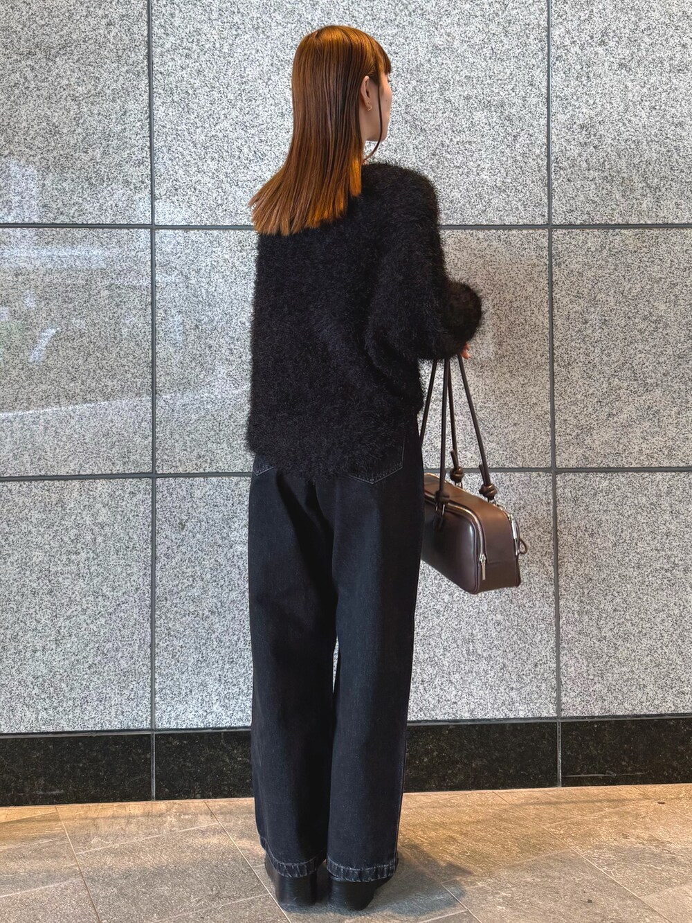 ブラック系のニット/セーター、ブラック系のデニムパンツ、ブラウン系のボストンバッグを着用したレディースの冬コーディネートの4枚目の写真