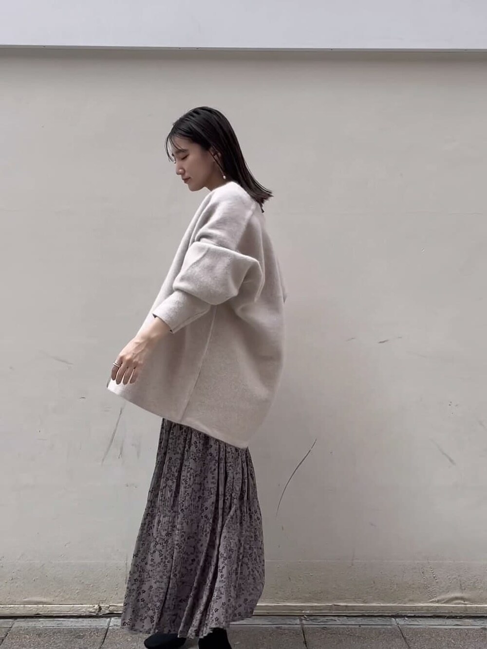 グレー系のワンピース、ホワイト系のカーディガン/ボレロ、ホワイト系のピアス（両耳用）を着用したレディースの秋コーディネートの8枚目の写真