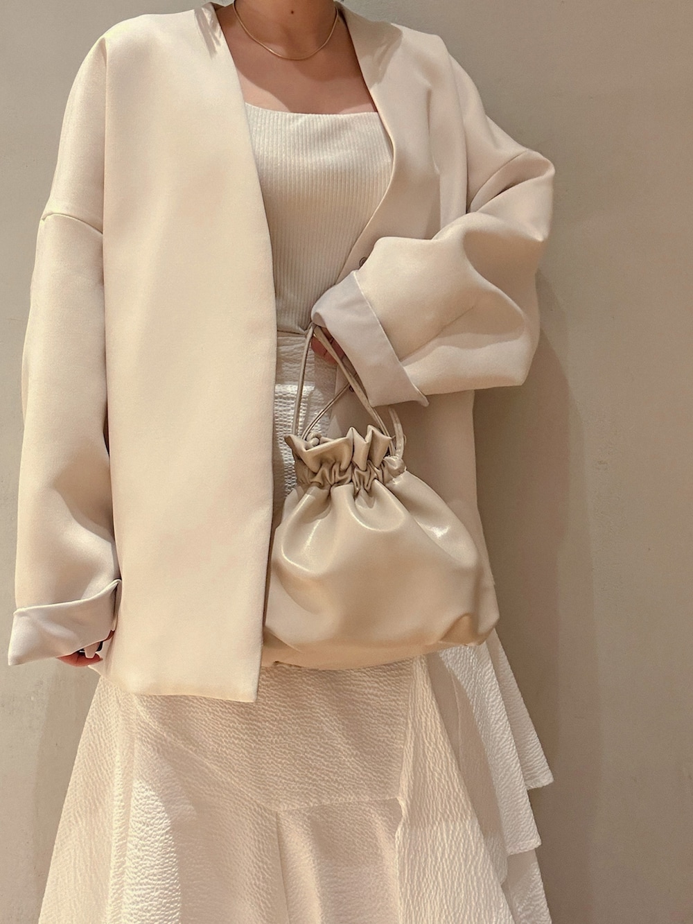 ブラウン系のノーカラーコート、ホワイト系のスカート、ホワイト系のサンダルを着用したレディースの春コーディネートの7枚目の写真