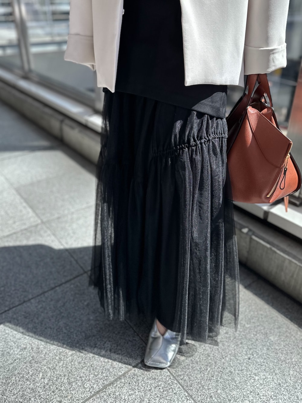 シルバー系のパンプス、ブラック系のスカート、ベージュ系のノーカラーコートを着用したレディースの春コーディネートの7枚目の写真