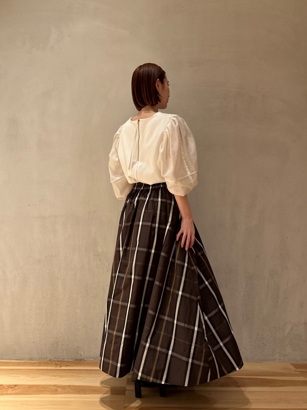 ホワイト系のTシャツ/カットソー、ブラウン系のスカート、ブラック系のパンプスを着用したレディースの春コーディネートの2枚目の写真