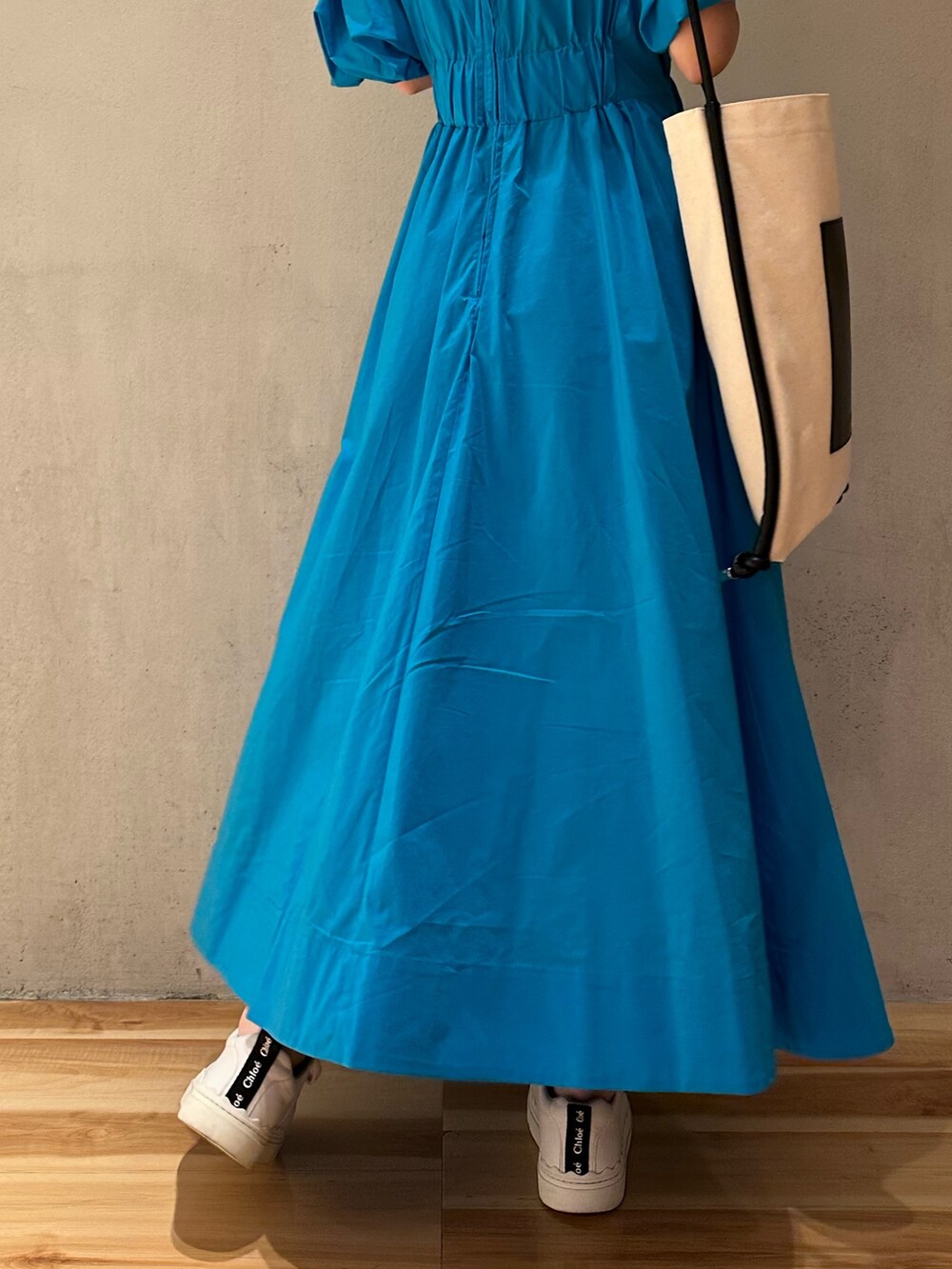 その他のトートバッグ、ブルー系のワンピース、ホワイト系のスニーカーを着用したレディースの春コーディネートの6枚目の写真