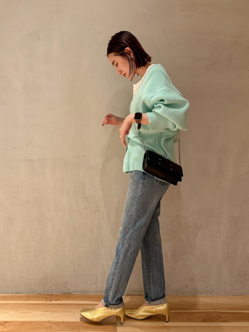 ブルー系のデニムパンツ、グリーン系のカーディガン/ボレロ、ホワイト系のTシャツ/カットソーを着用したレディースの冬コーディネートの2枚目の写真