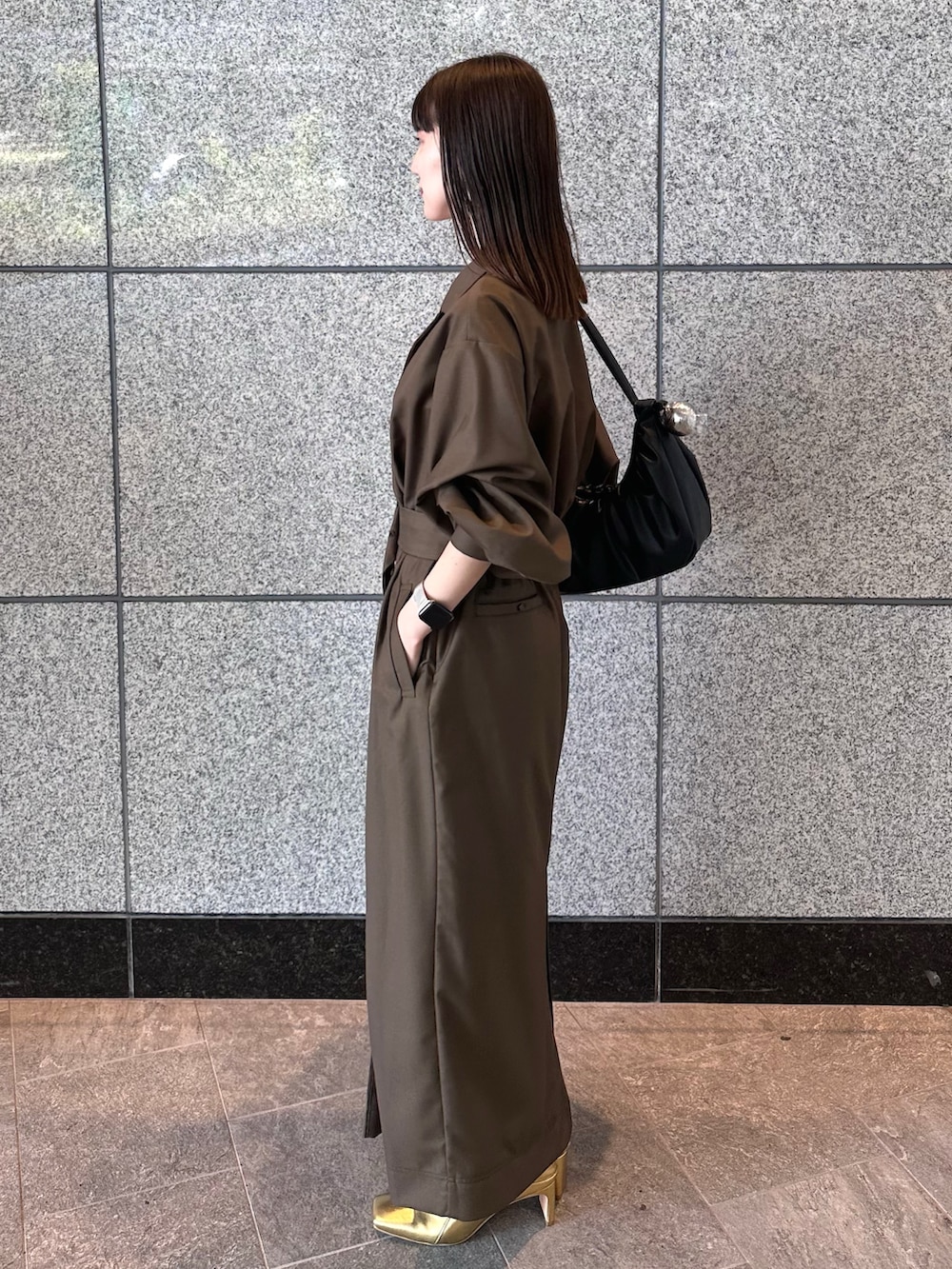 ブラウン系のワンピース、ゴールド系のブーツ、ブラック系のハンドバッグを着用したレディースの秋コーディネートの4枚目の写真