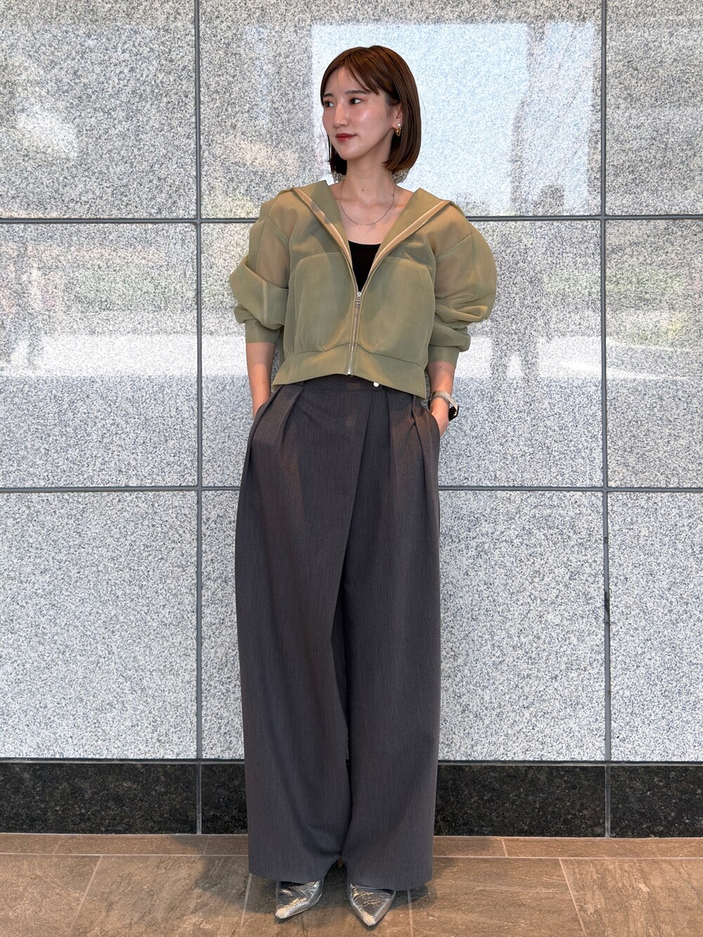 グリーン系のブルゾン、グレー系のその他パンツ、シルバー系のパンプスを着用したレディースの夏コーディネートの2枚目の写真