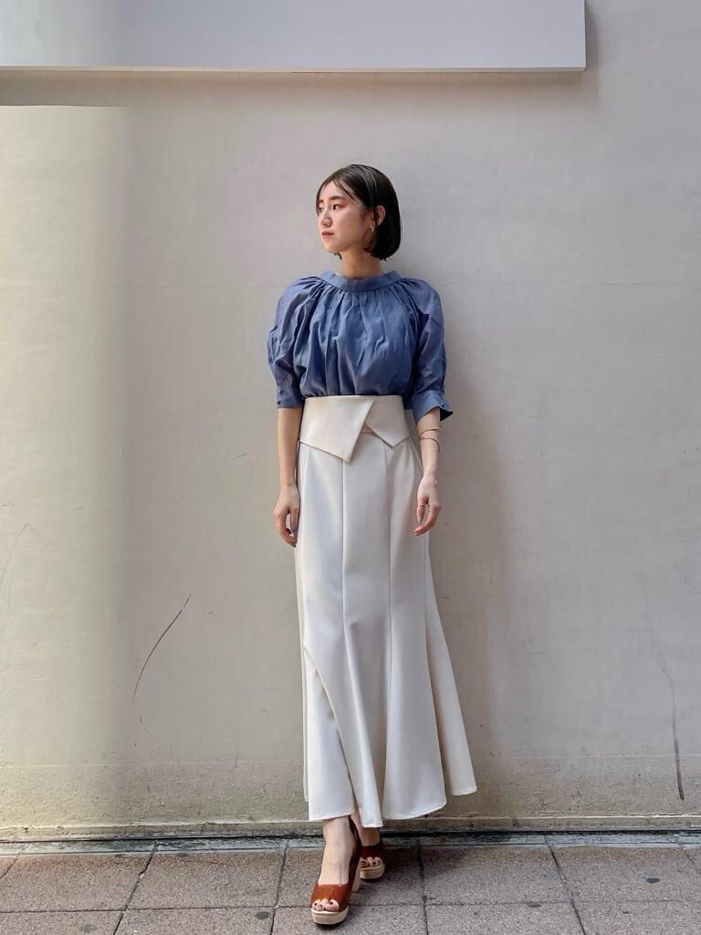 ホワイト系のスカート、ブラウン系のパンプス、ブルー系のシャツ/ブラウスを着用したレディースの春コーディネートの2枚目の写真