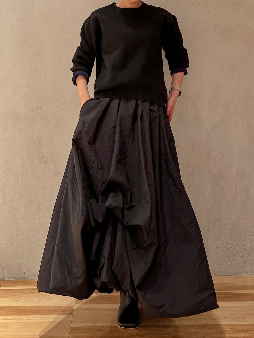 ブラック系のスカート、ブラック系のニット/セーター、ブラック系のブーツを着用したレディースの夏コーディネートの3枚目の写真