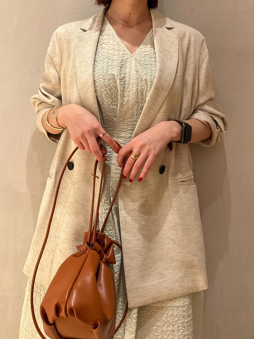 ベージュ系のテーラードジャケット、グリーン系のワンピース、ホワイト系のサンダルを着用したレディースの冬コーディネートの6枚目の写真