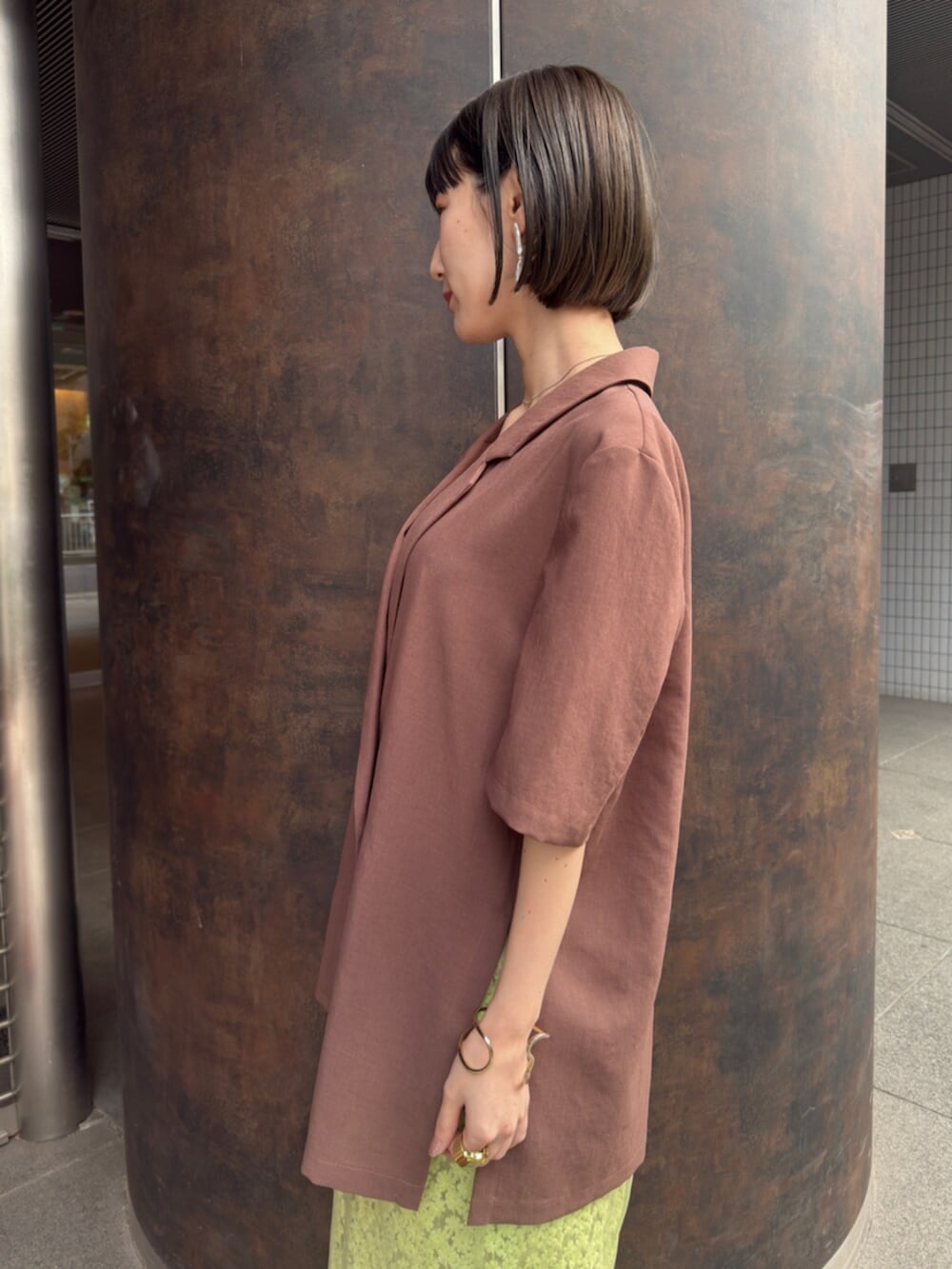 シルバー系のパンプス、ブラウン系のテーラードジャケット、グリーン系のスカートを着用したレディースの春コーディネートの6枚目の写真