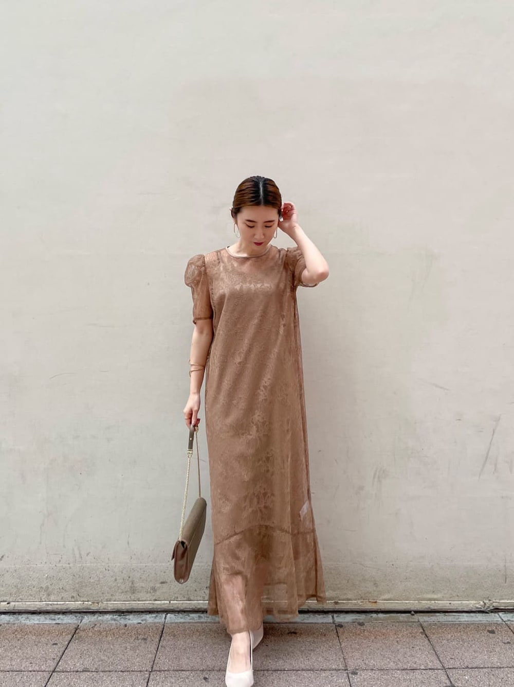ベージュ系のパンプス、ゴールド系のクラッチバッグ、ベージュ系のドレスを着用したレディースの春コーディネートの2枚目の写真